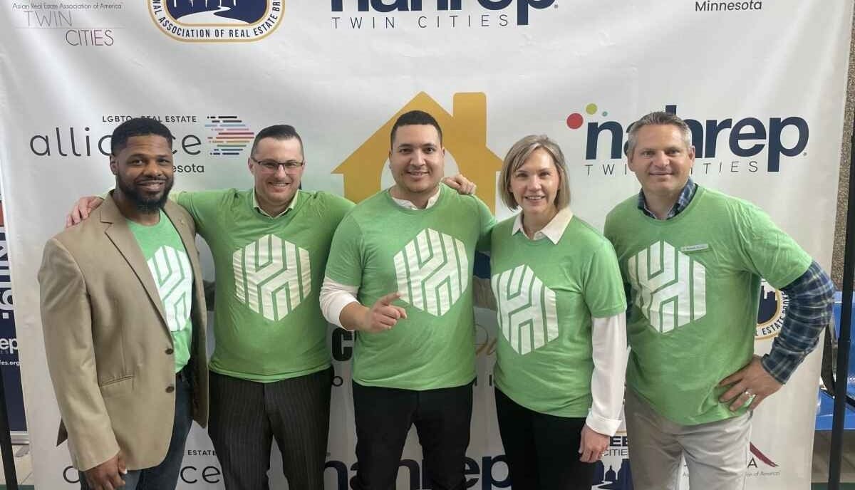 Five people wearing Huntington shirts standing in front of sign