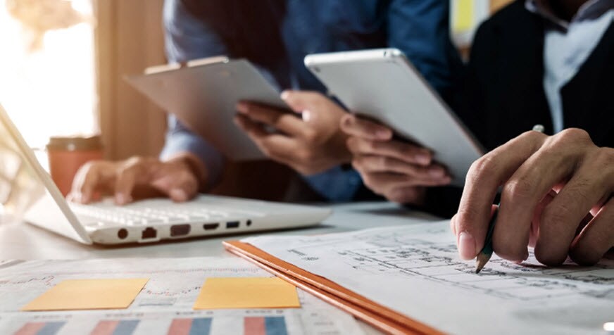 People making notes on paper and digital devices.