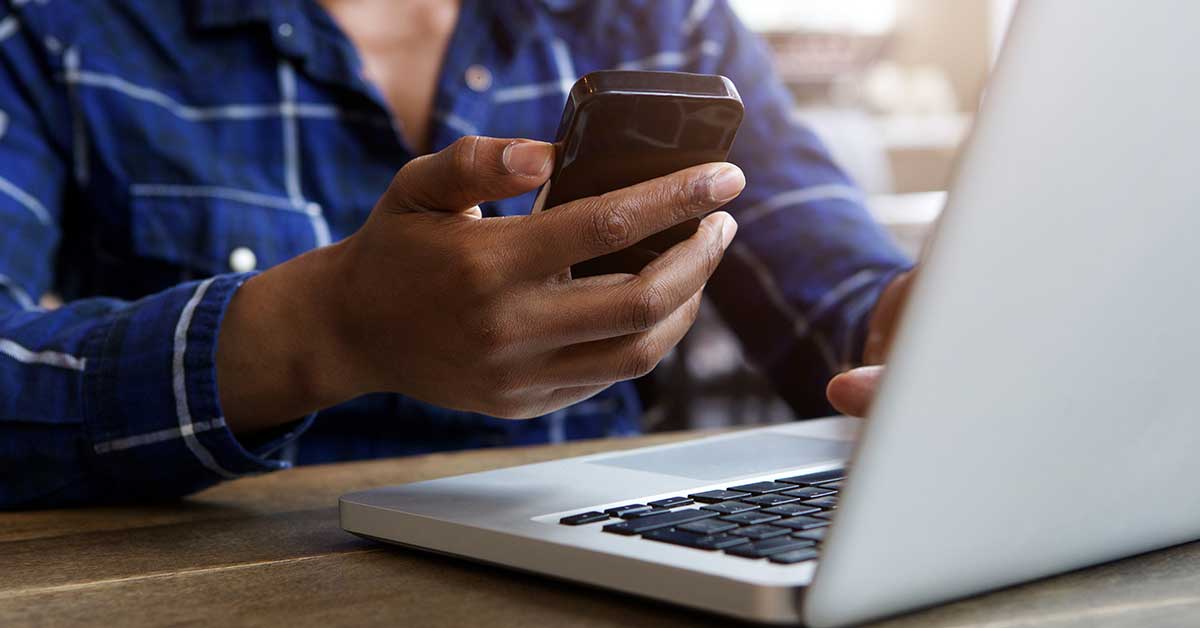 a man researches how to set up direct deposit on his laptop and smartphone