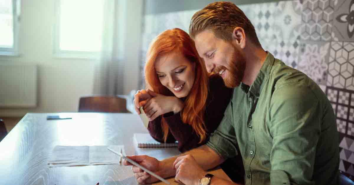 a couple looks at their joint checking account on a tablet