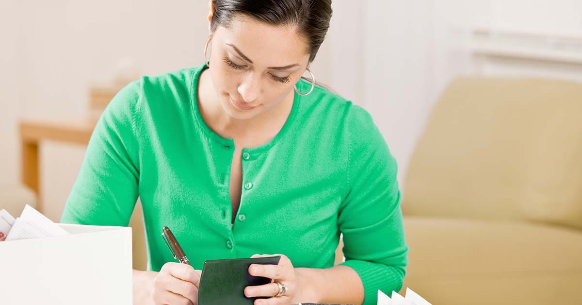 woman in green shirt filling out a check