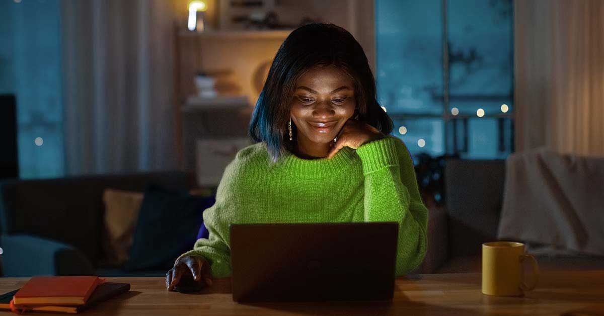 woman in green sweater looking at laptop