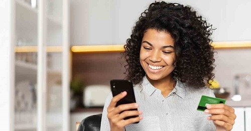 a young woman enters her credit card information into her smartphone