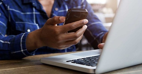 a man researches how to set up direct deposit on his laptop and smartphone