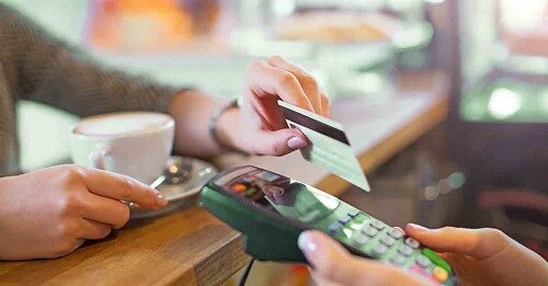 a customer hands over a debit card to a cashier