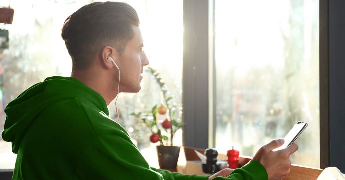 Man in green sweatshirt looking at phone