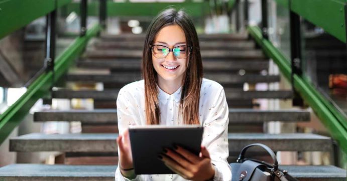 Woman sitting on stairs looking at tablet