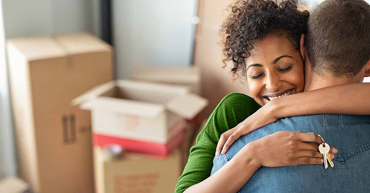 couple hugging in front of boxes and holding key