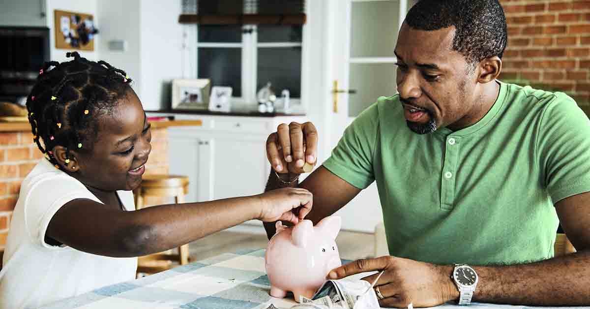 a father helps his young daughter deposit coins into her piggy bank