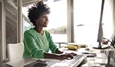 Woman in green sweater smiling at computer