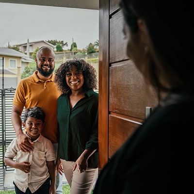 Smiling family standing at their front door.